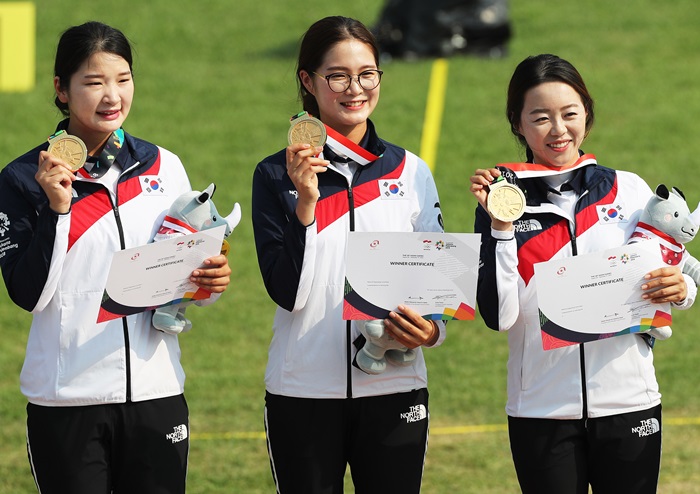 3 vận động viên Hàn Quốc Kang Chaeyoung, Lee Eungyeong và Chang Hyejin (từ bên trái) đang nâng lên huy chương vàng và tươi cười trong lễ trao thưởng môn bắn cung đồng đội nội dung Recurve nữ đã được tổ chức ở sân bắn cung của sân vận động Gelora Bung Karno, Jakarta, Indonesia vào ngày 27/8. (Ảnh: Yonhap News)