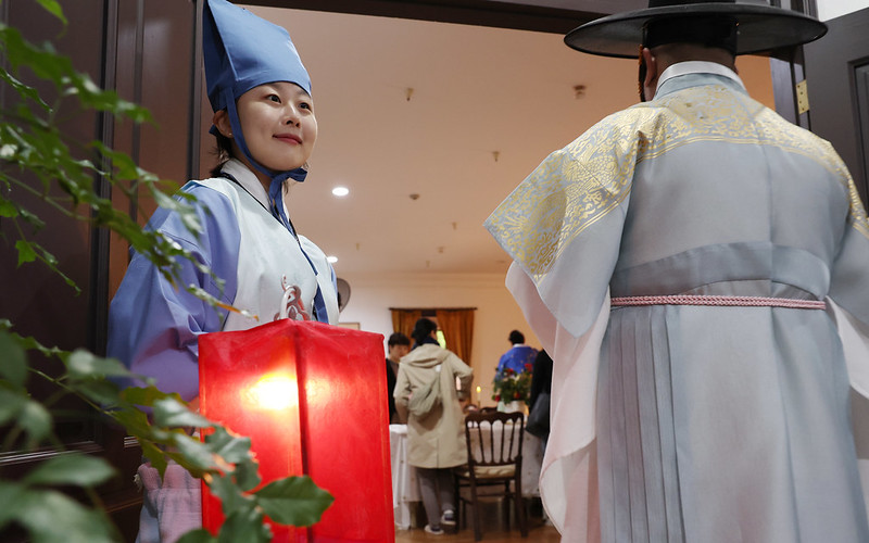 Một nhân viên mặc bộ Hanbok (trang phục truyền thống Hàn Quốc) hướng dẫn những du khách tham gia chương trình “Bàn ăn của hoàng đế” (tiếng Anh: The Emperor’s Dining Table) vào nơi tổ chức bữa tiệc. (Ảnh: Lee Jeong Woo / Korea.net)