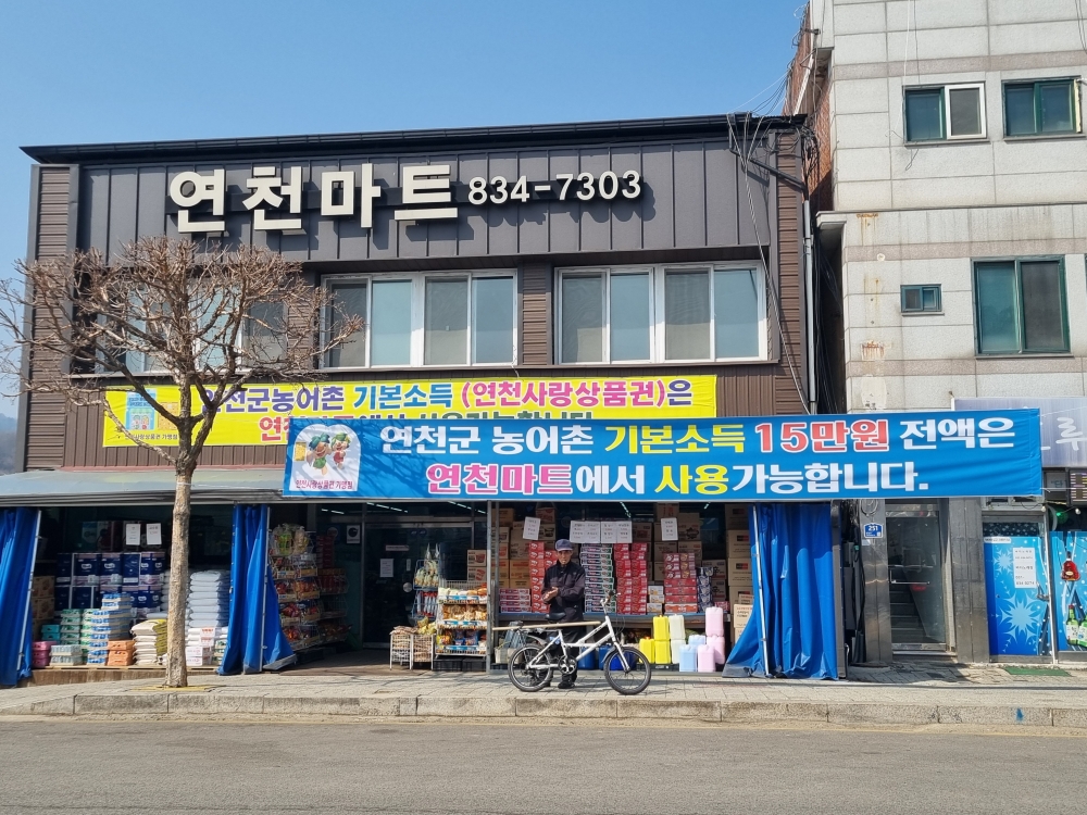 Trước một tiệm tạp h&oacute;a ở huyện Yeoncheon County, tỉnh Gyeonggi Province, c&oacute; treo d&ograve;ng th&ocirc;ng b&aacute;o: &ldquo;To&agrave;n bộ khoản thu nhập cơ bản n&ocirc;ng th&ocirc;n 150.000 won c&oacute; thể sử dụng tại đ&acirc;y&rdquo;. (Ảnh:&nbsp;Aisylu Akhmetzianova / Korea.net).