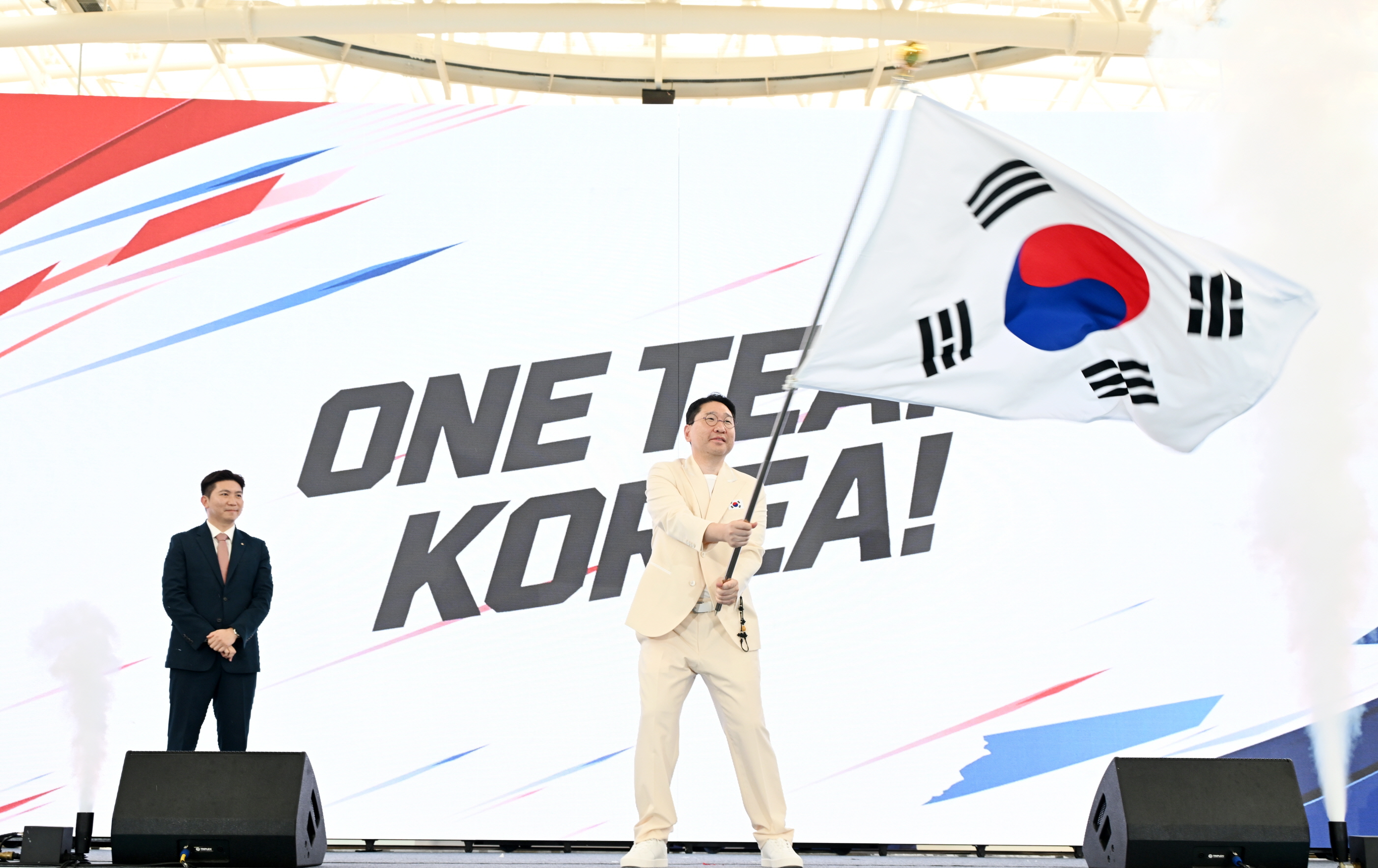 Trưởng đoàn thể thao Hàn Quốc tham dự Đại hội Thể thao châu Á Aichi-Nagoya 2026 Lee Sang-hyun nhận và phất cờ đoàn tại lễ xuất quân diễn ra ngày 3/9 tại Làng Vận động viên Jincheon, tỉnh Chungcheongbuk. (Ảnh: Ủy ban Olympic và Thể thao Hàn Quốc)