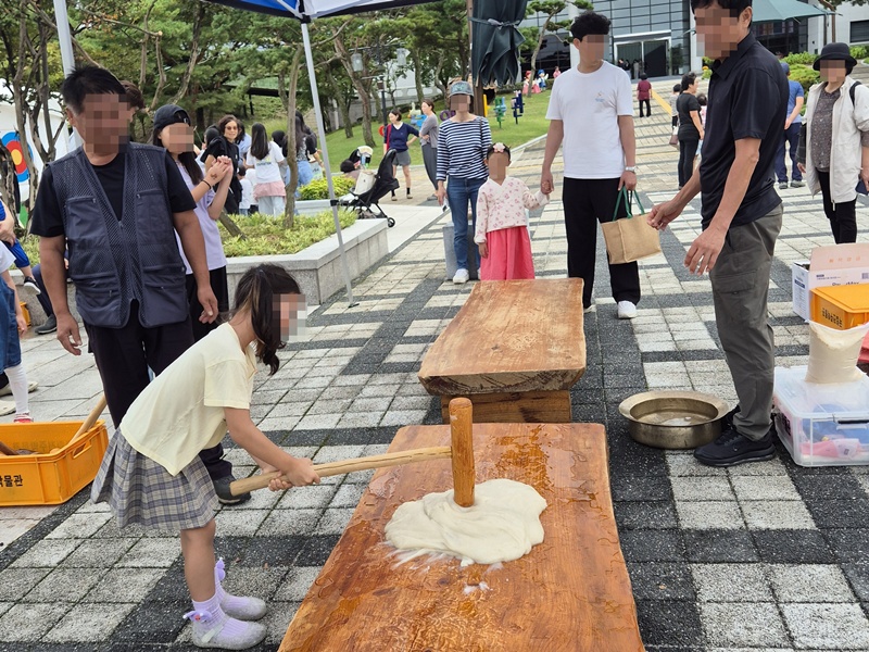 Du khách trải nghiệm giã bánh bằng chày gỗ trong khuôn khổ chương trình “Sân chơi dân gian Hangawi”, được tổ chức từ ngày 3~7/10/2025 tại Bảo tàng Quốc gia Jeonju ở quận Wansan-gu, thành phố Jeonju, tỉnh Jeonbuk. (Ảnh: Bảo tàng Quốc gia Jeonju)