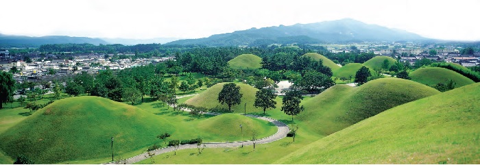 <B>Gyeongju Historic Areas.</b> Gyeongju was the capital of Silla for about one millennium. The city still contains a wealth of archaeological remains from the Kingdom, and hence is often dubbed as “a museum without walls or roof.” The photo shows a scene of the Silla mound tombs located in the city.