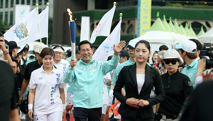 인천 아시아경기대회 성화를 든 박선규 성화봉송단장이 16일 임오경 서울시청 핸드볼팀 감독과 함께 서울시청 앞에 마련된 성화 안치식장으로 들어서고 있다. 