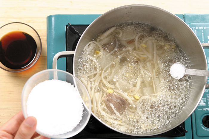 Đổ nước dùng vào nồi, cho thịt bò và củ cải, cây dương xỉ, rễ doraji, giá đậu nành vào đun sôi rồi nêm nếm gia vị bằng muối và nước sốt đậu nành. Để ý không đun lâu làm giá đậu nành dai.