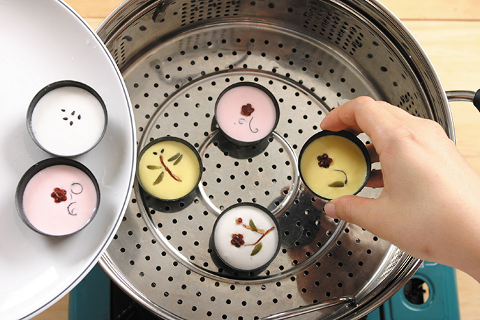 Bôi dầu ăn vào khuôn bột. Cho bột vào khoảng 2/3 khuôn và cho những miếng táo tàu, nấm và hạt bí ngô lên để trang trí sau đó cho vào hấp.