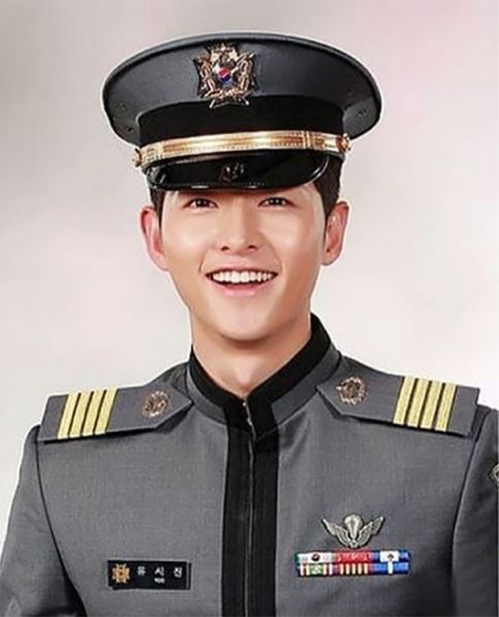 Song Joong-ki clothing the cadet uniform smiles largely .