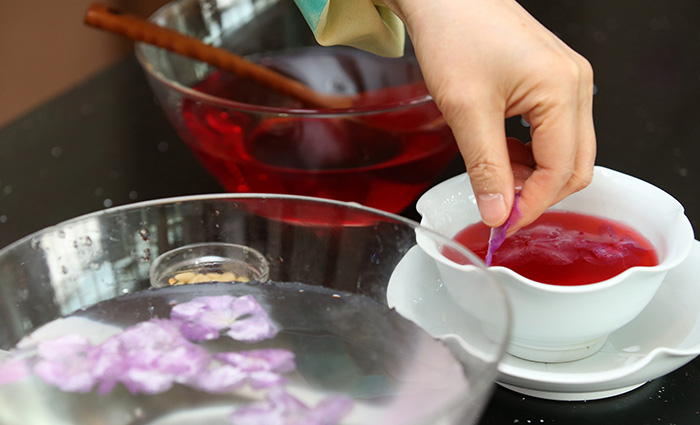 Cho cánh hoa đỗ quyên đã lăn bột vào nước sôi khoảng 1 - 2 giây rồi lấy ra, thả vào nước lạnh để giữ màu hoa.