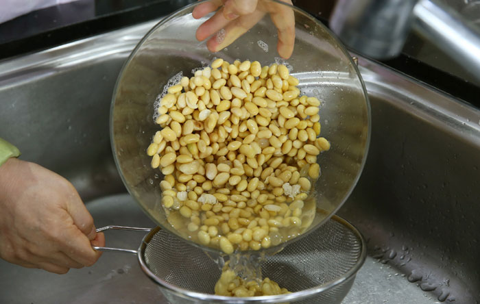 Wash the soybeans and soak them in water for about eight hours. Drain them with a strainer to remove the water.