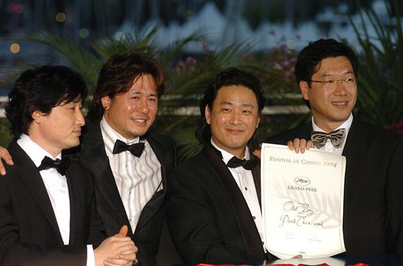 Từ trái sang phải: nhà sản xuất Lim Seung-yong (hiện là CEO của Yong Film), diễn viên Choi Min-sik, đạo diễn Park Chan-wook và giám đốc hình ảnh Chung Chung-hoon chụp ảnh kỷ niệm sau khi bộ phim 'Oldboy' giành giải Grand Prix tại Lễ trao giải Liên hoan phim Cannes lần thứ 57, diễn ra ngày 22/5/2004 (giờ địa phương) tại Palais des Festivals ở Cannes, Pháp. (Ảnh: Thư viện truyền thông của Liên hoan phim Cannes)